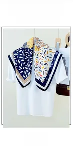 Detail of silk-like square scarf featuring blue borders and colorful leaf print patterns
