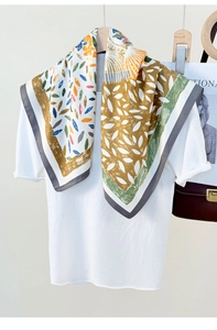 Detail of colorful leaf print faux silk square scarf draped on a white tee with bag