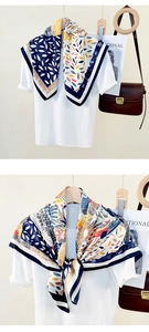 Detail of multi-color patterned square silk scarf with navy border on white shirt