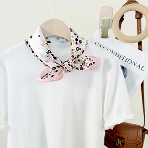 Silk scarf with pink floral print on white t-shirt hanging on a wooden hanger