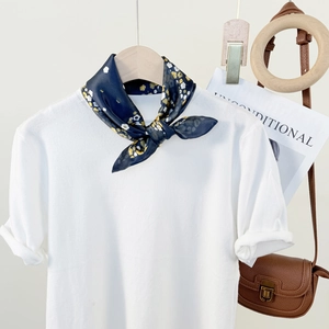 White short sleeve knit top paired with a navy floral silk scarf on a wooden hanger