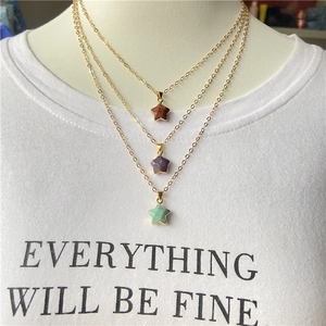 Set of three gold-tone star pendant necklaces with natural stone crystals on a model