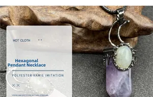 Macro detail of hexagonal purple crystal pendant with moon accent and green gem