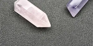 Close-up of polished pink quartz and purple amethyst hexagonal crystal prism pendants