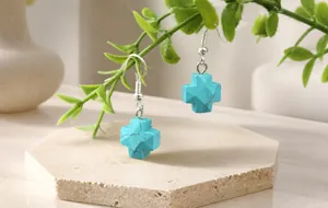 Detailed shot of cross earrings featuring natural turquoise and agate stones on hooks