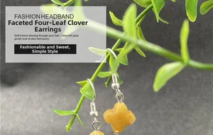 Detailed view of yellow faceted clover earrings hanging on a green plant branch