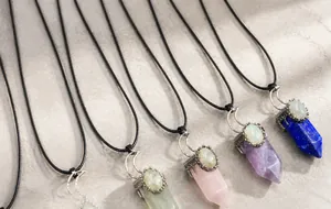 Close-up of hexagonal crystal pendants with crescent moon accents on black cord necklaces