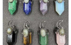 Close-up of hexagonal crystal pendants featuring crescent moon metal details and various stones