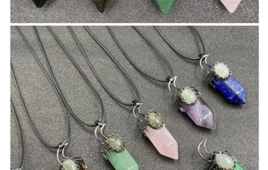 Macro shot of assorted gemstone hexagonal prism pendants with moon-shaped silver metal accents