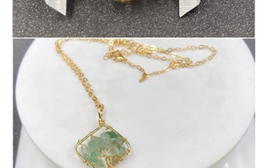 Macro detail of Tree of Life crystal necklace with green stone and gold wire wrapping