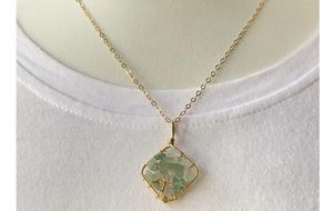 Macro detail of wire-wrapped tree of life pendant with green aventurine on white t-shirt