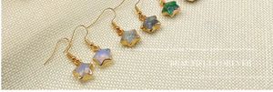 Detailed view of gold-rimmed star-shaped crystal earrings on natural linen fabric
