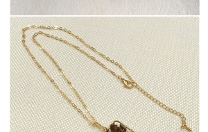 Close-up of golden chain necklace with lobster clasp and brown stone pendant details