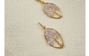 Close-up of handmade tree of life pendants with gold wire and purple amethyst stones