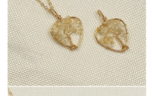 Detailed view of handmade heart-shaped tree of life crystal pendants on knit fabric