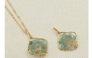 Detail of handmade Tree of Life crystal pendant with gold wire wrapping on beige fabric