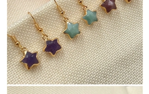 Close-up of star-shaped crystal earrings with gold plating on rustic linen background