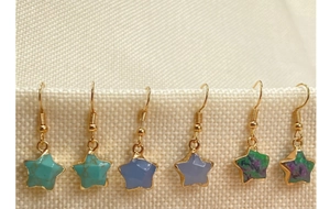 Detail of three pairs of star-shaped crystal drop earrings with gold plated edges