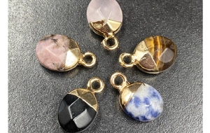 Detailed macro view of faceted natural stone pendants with gold-plated edges and metal loops