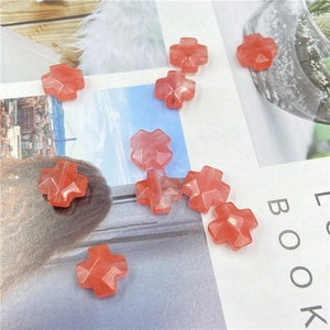 Close-up of translucent orange cross-shaped beads with faceted texture for DIY jewelry