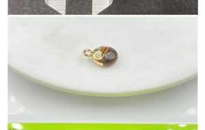 Macro shot of faceted tiger eye gemstone pendant with gold plated rim on a scale