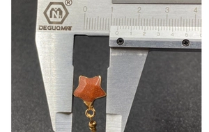 Macro shot showing 11mm star-shaped goldstone pendant measured with a caliper