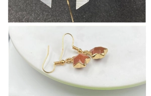 Detail of star-shaped gold-plated drop earrings with sparkling goldstone and French hooks