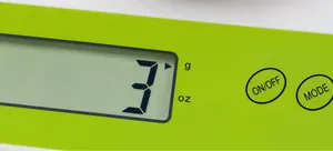 Detail of digital kitchen scale LCD screen showing 3g with green plastic casing