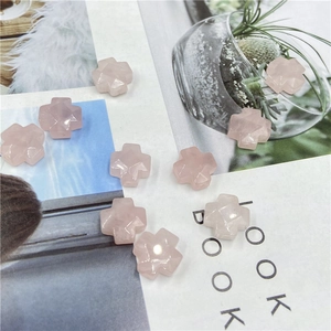 Faceted pink quartz cross-shaped loose beads for DIY jewelry making on a magazine background