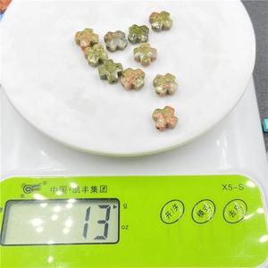 Macro shot of 11 green and pink natural stone cross beads on a scale for jewelry DIY