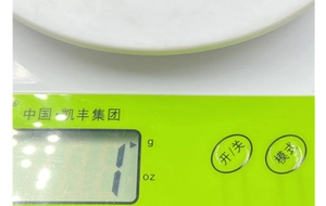 Dettaglio di una bilancia da cucina digitale con corpo verde, vassoio bianco e display LCD