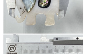 Detail view of elephant pendant size measurement with abalone shell inlay using a caliper