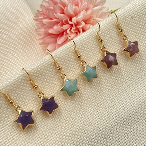 Star-shaped gold-plated crystal earrings in purple, green, and red on a beige background