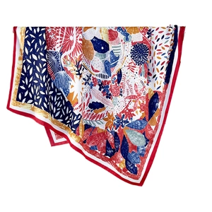 Colorful silk-like square scarf with abstract floral prints and red border on white background