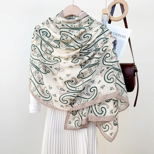 Lightweight paisley print shawl in beige and green, draped over a wooden hanger set