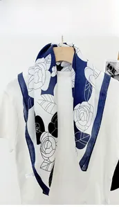 Detailed view of a camellia floral silk scarf draped over a white t-shirt on a hanger