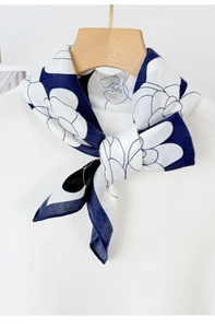 Close-up of blue camellia print silk scarf tied on a white knit sweater collar