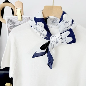 Elegant navy blue silk scarf with white floral print tied on a minimalist white T-shirt
