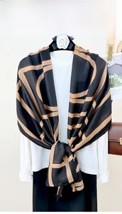 Detail view of black silk scarf with brown geometric lines over a white t-shirt
