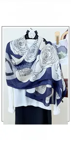 Detailed close-up of a long cotton linen floral scarf with blue rose prints on white fabric