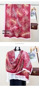 Detail of red faux cashmere shawl featuring elegant feather prints and pink edges