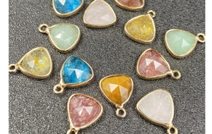 Macro detail of faceted triangle charms with gold plated edges for DIY jewelry making