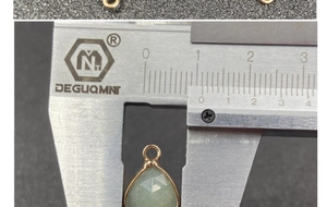 Macro shot of a 10x14mm faceted green teardrop stone pendant measured with a caliper