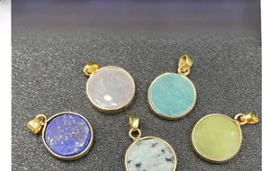 Detail of round quartz and stone pendants with golden metal edges in five varied colors