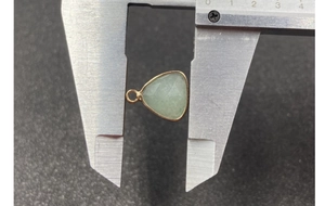 Macro shot measuring faceted green water drop gemstone with gold bezel for DIY jewelry