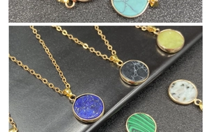 Close-up of multiple round gemstone pendants with gold plating on a black background