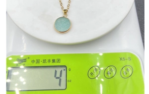 Detailed view of round light blue stone pendant necklace weighing 4 grams on scale