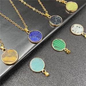 Variety of round natural stone pendants with gold metal frames on black display stand