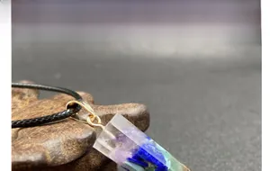 Makroaufnahme von Chakra-Harzanhänger mit Naturbruchsteinen und schwarzer Kordel
