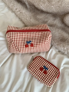 Detail of red checkered cherry embroidery makeup bag set on soft decorative texture